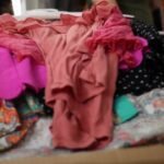 Close up of clothing piling up on bedroom bed – hoarding concept