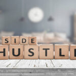 Side hustle sign on a plank table in a decorative room with a clock